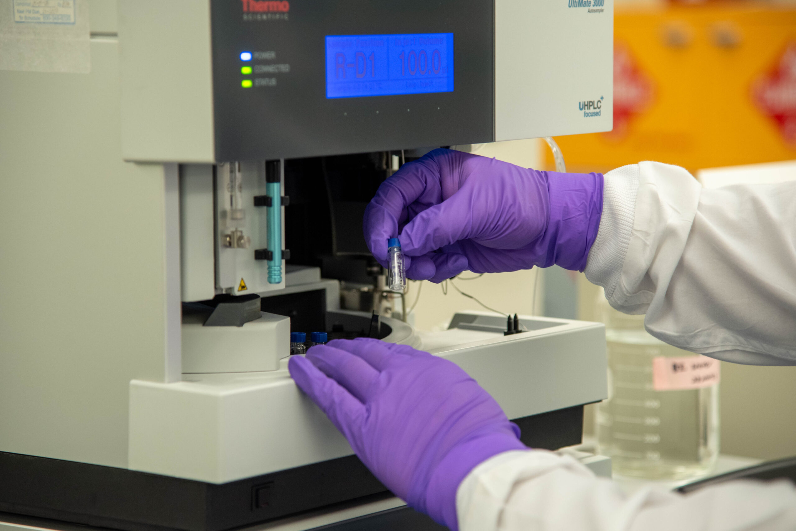 Operator retrieving a sample vial from the HPLC (High Performance Liquid Chromatography) system